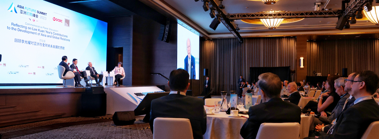 Audience watches a panel discussion at the Asia Future Summit on a stage with large screens.